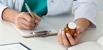 Doctor haciendo una receta con el medicamento en la mano