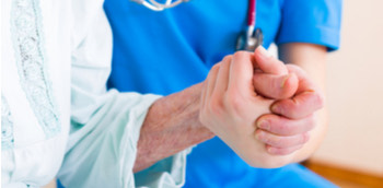 Doctora sujetando la mano de una paciente mayor