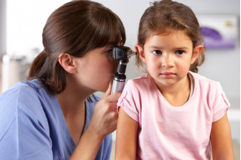 Otorrinolaringóloga mirando la cavidad auditiva de una niña