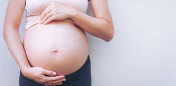 Mujer en fase avanzada del embarazo con la barriga al aire
